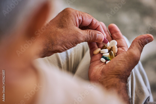 Pills, medicine and healthcare of senior man taking daily capsules for chronic illness, cancer or health. Wellness, medication and sick elderl with medical drugs, vitamins or supplements in his hand photo