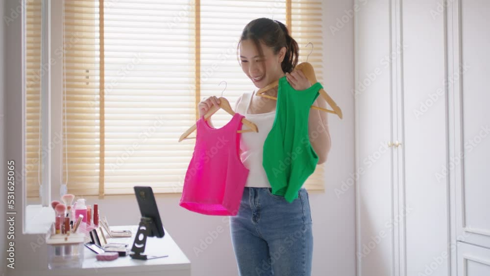 Asia Gen Z influencer youtuber girl live talk selling clothes closet on IG instagram reel selfie blog vlog. Young woman blogger page vlogger record video home camera showing fashion store tiktok shop.
