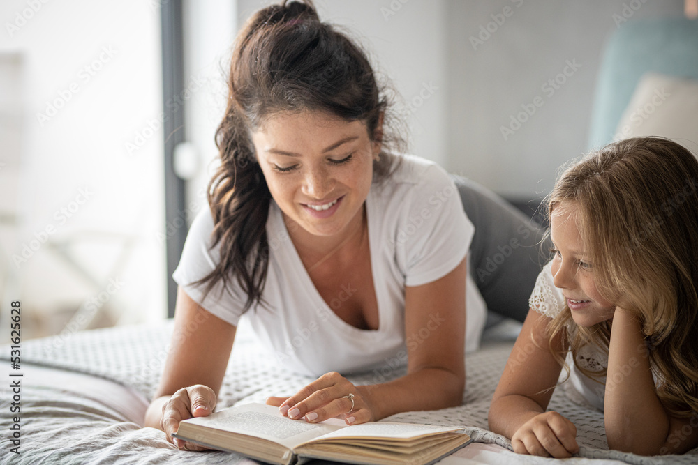 Pregnant mother playing with daughter They are reading a book, playing and laughing Pregnant mother playing with daughter They are reading a book, playing and laughing