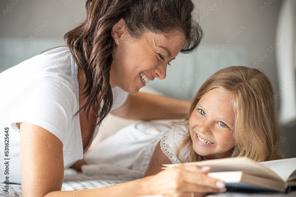 Pregnant mother playing with daughter They are reading a book, playing and laughing Pregnant mother playing with daughter They are reading a book, playing and laughing