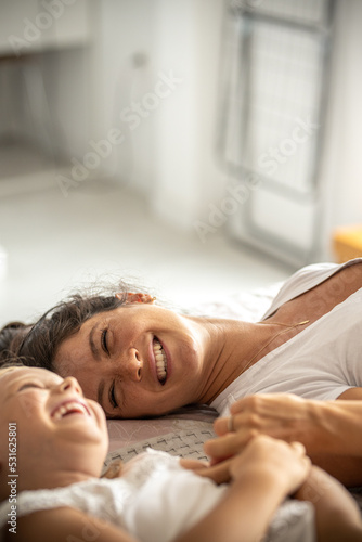 Mother and daughter laying on bed and laughing