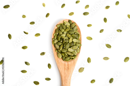 Pumpkin seeds on white background, top view. Pumpkin seeds in wooden spoon. Healthy eating
