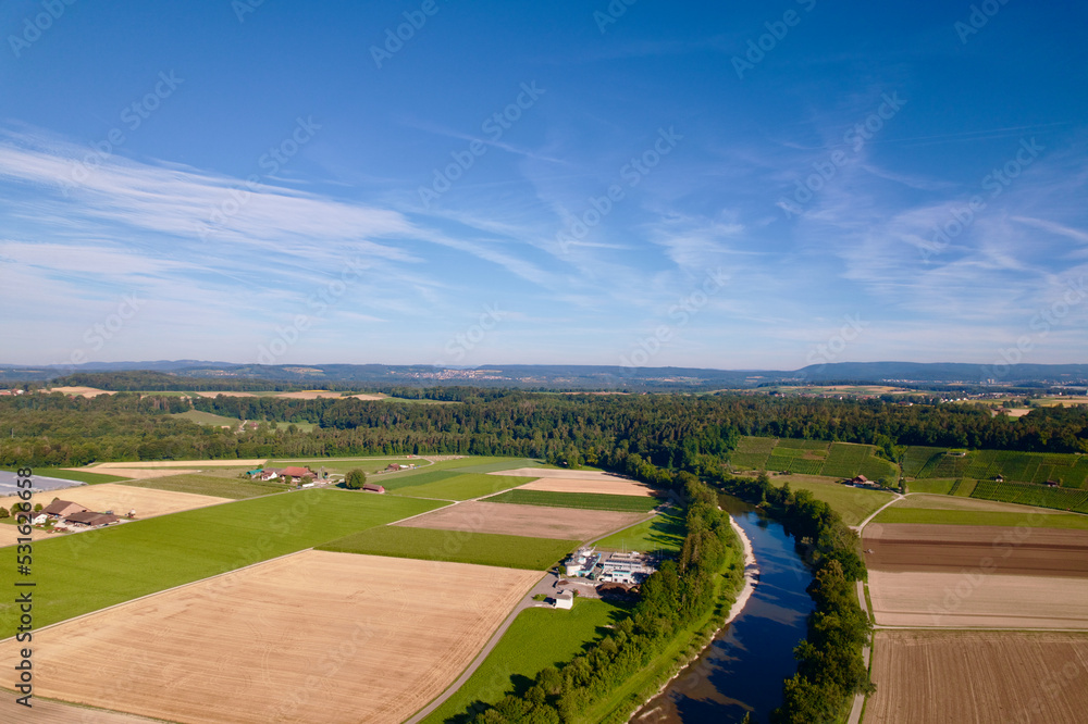 Aerial view of harvest of agricultural fields with Thur River at village of Andelfingen, Canton Zürich, on a sunny summer morning. Photo taken July 12th, 2022, Andelfingen, Switzerland.