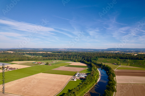 Aerial view of harvest of agricultural fields with Thur River at village of Andelfingen, Canton Zürich, on a sunny summer morning. Photo taken July 12th, 2022, Andelfingen, Switzerland.