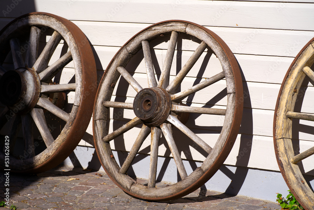 Wooden wheels of carriage leaned against wall of house on a sunny summer day at rural village Andelfingen, Canton Zürich. Photo taken July 12th, 2022, Andelfingen, Switzerland.