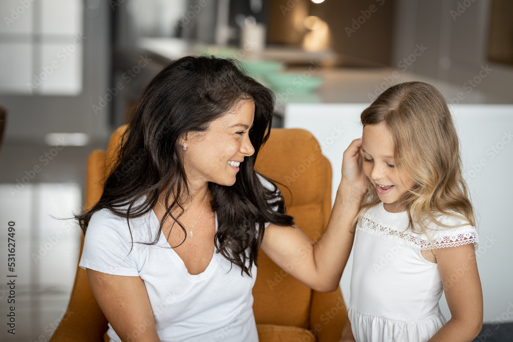 Mother with her little daughter, talking in the living room