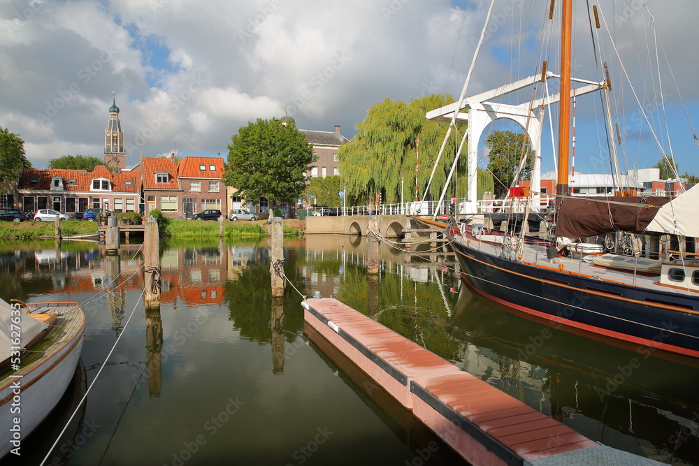 Sailing boats viewed from Noorderkade street in Enkhuizen, West Friesland, Netherlands, with Compagniesbrug drawbridge on the right and the tower of Zuiderkerk (or St Pancraskerk) in the background Sailing boats viewed from Noorderkade street in Enkhuizen, West Friesland, Netherlands, with Compagniesbrug drawbridge on the right and the tower of Zuiderkerk (or St Pancraskerk) in the background