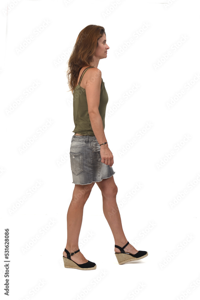 side view of a woman with denim skirt and spadrille walking on white background side view of a woman with denim skirt and spadrille walking on white background