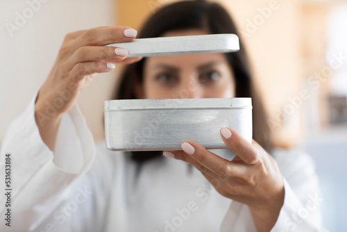 Scientist holding metal box, focus on foreground