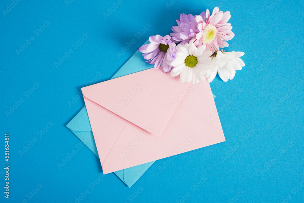 pink and blue envelopes and flowers on blue background copy space mock up pink and blue envelopes and flowers on blue background copy space mock up