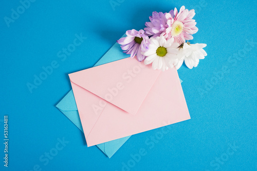 pink and blue envelopes and flowers on blue background copy space mock up