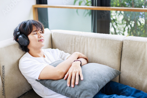 Asian Male resting on sofa with headphones at home. Time to relax and leisure activities