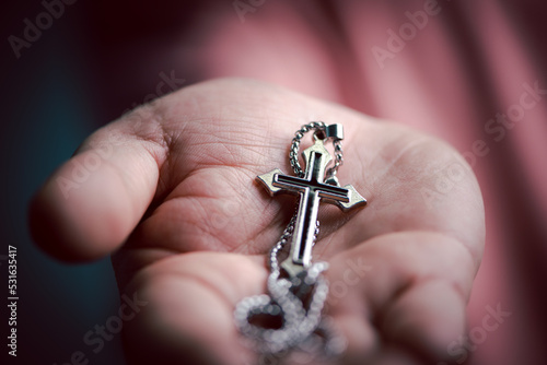 Spiritual christian hand holding Jesus cross necklace in the palm with faith and believe. 