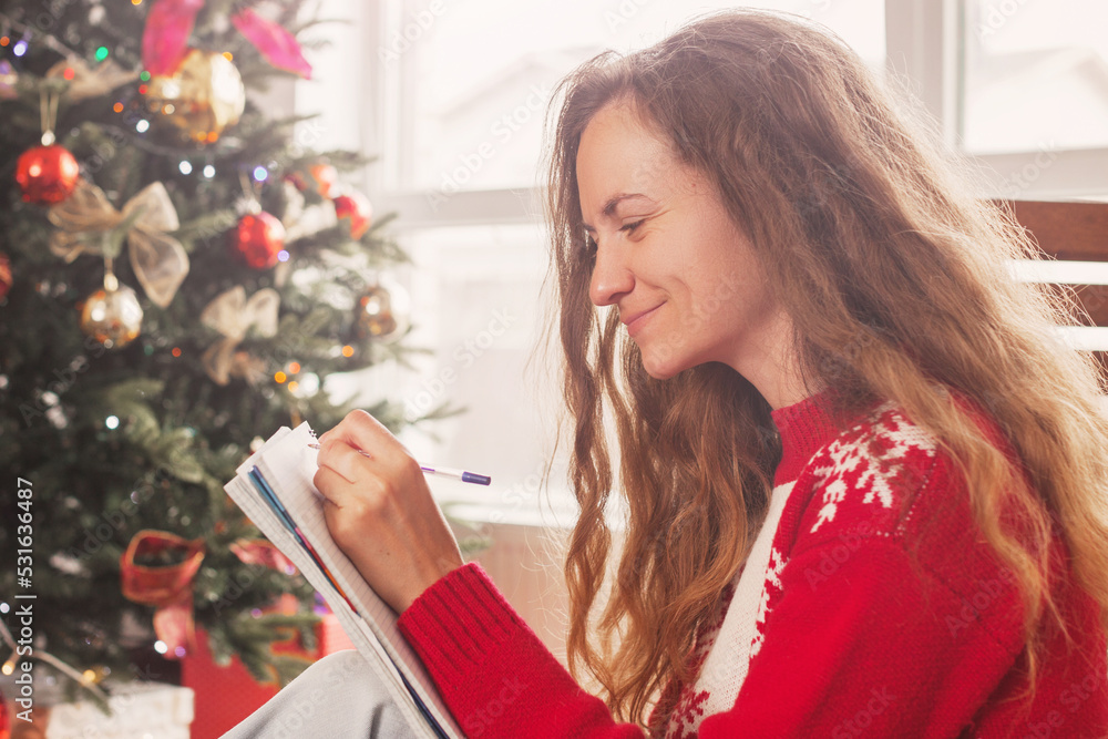 Woman writing shopping list, Christmas letter or wish list