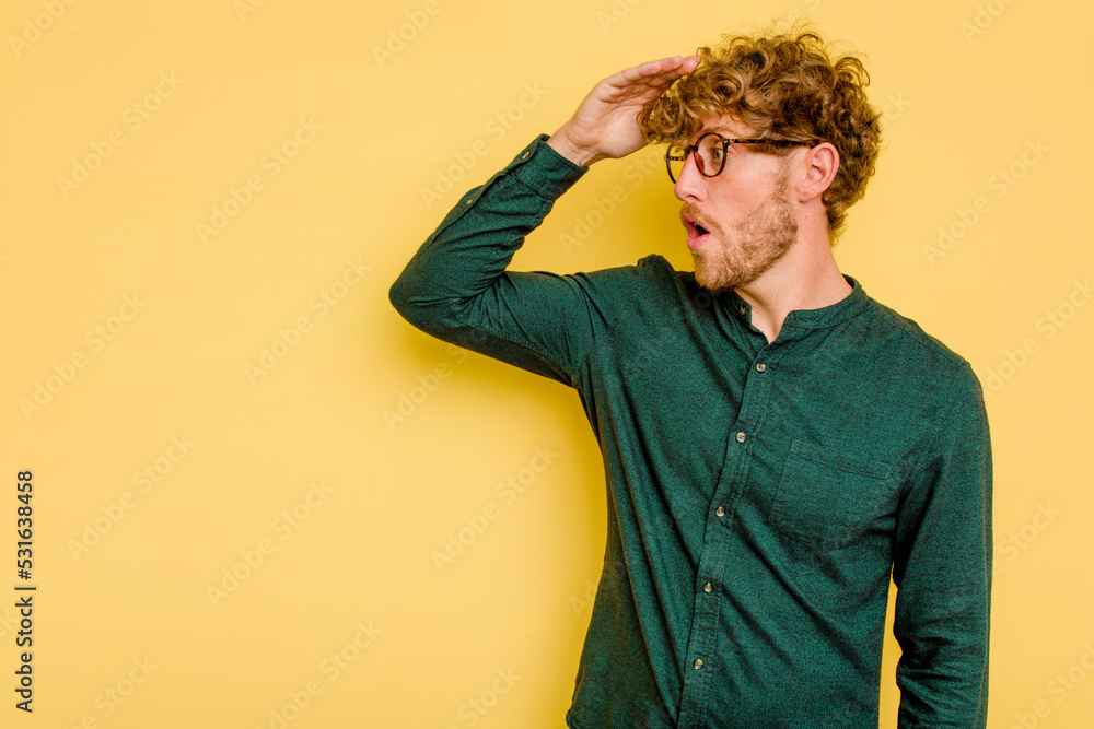 Young caucasian man isolated on yellow background looking far away keeping hand on forehead. Young caucasian man isolated on yellow background looking far away keeping hand on forehead.