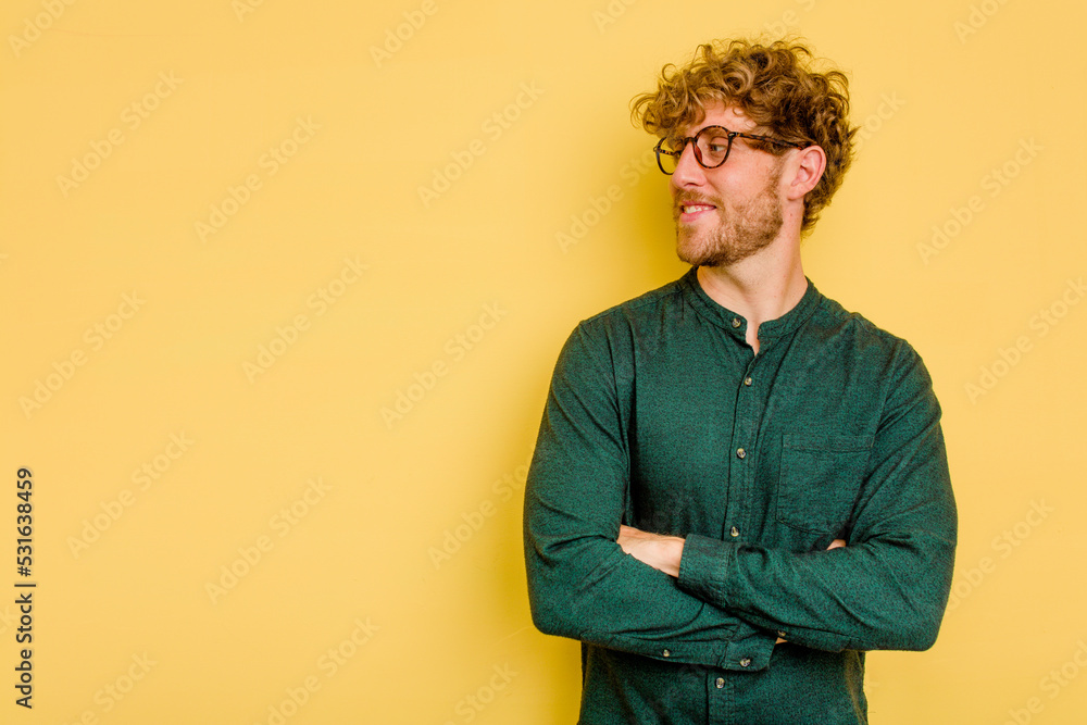 Young caucasian man isolated on yellow background smiling confident with crossed arms. Young caucasian man isolated on yellow background smiling confident with crossed arms.