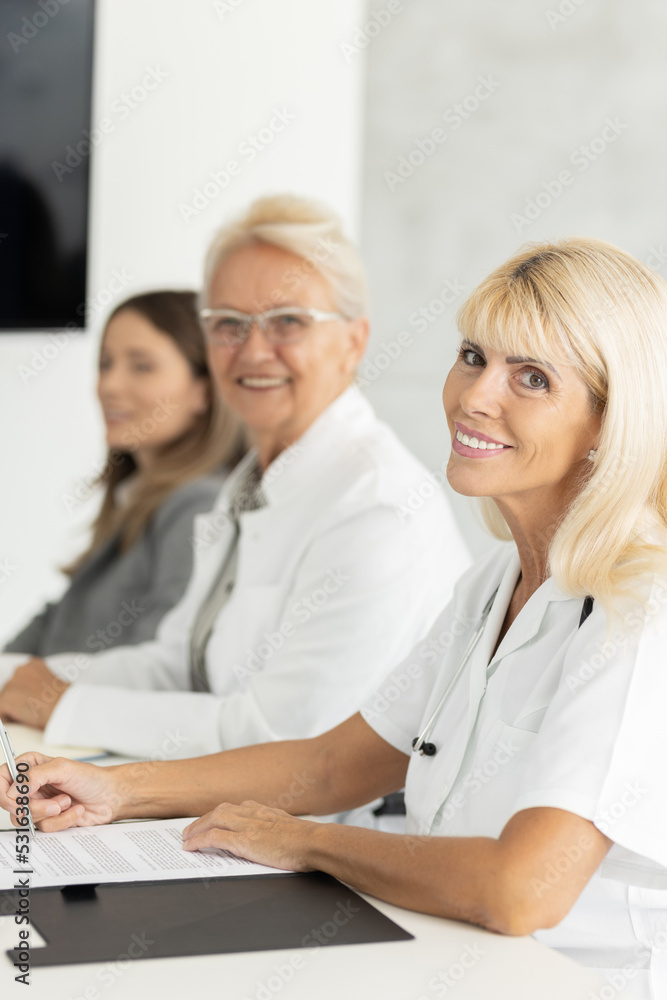Doctors and managers on business meeting Doktors looking on camera, focus on senior female doctor