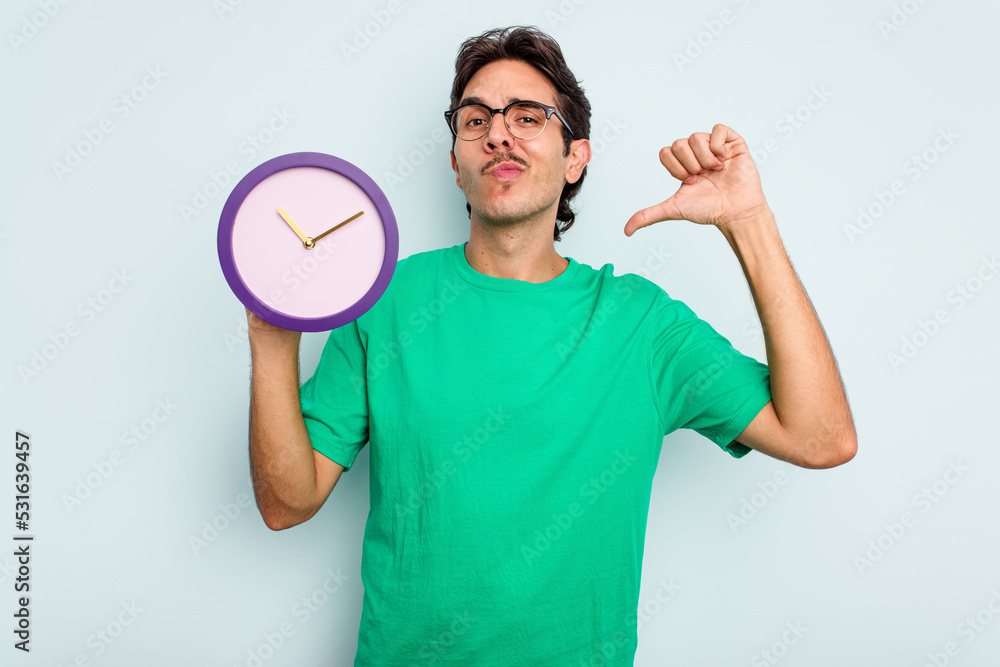 Young hispanic man holding a clock isolated on white background feels proud and self confident, example to follow. Young hispanic man holding a clock isolated on white background feels proud and self confident, example to follow.