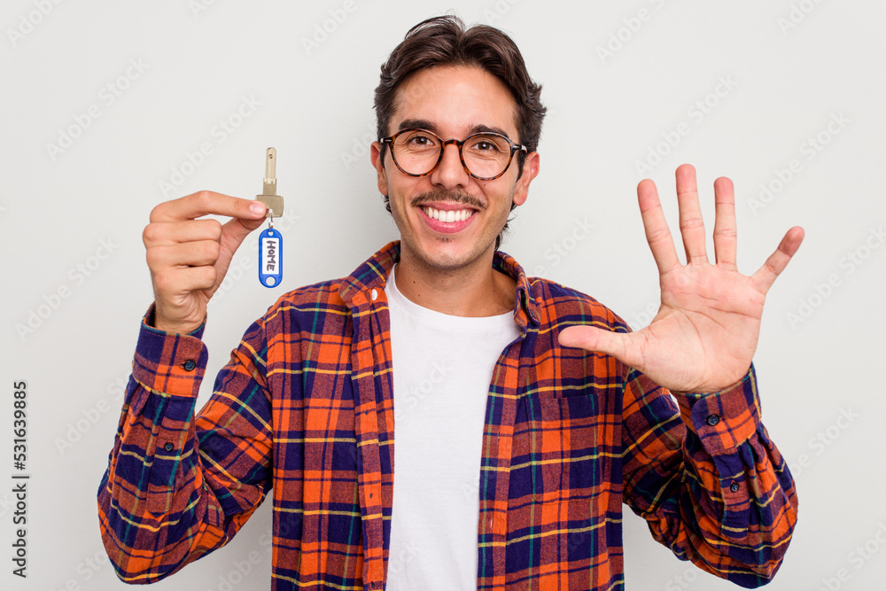 Young hispanic man holding home keys isolated on white background smiling cheerful showing number five with fingers. Young hispanic man holding home keys isolated on white background smiling cheerful showing number five with fingers.
