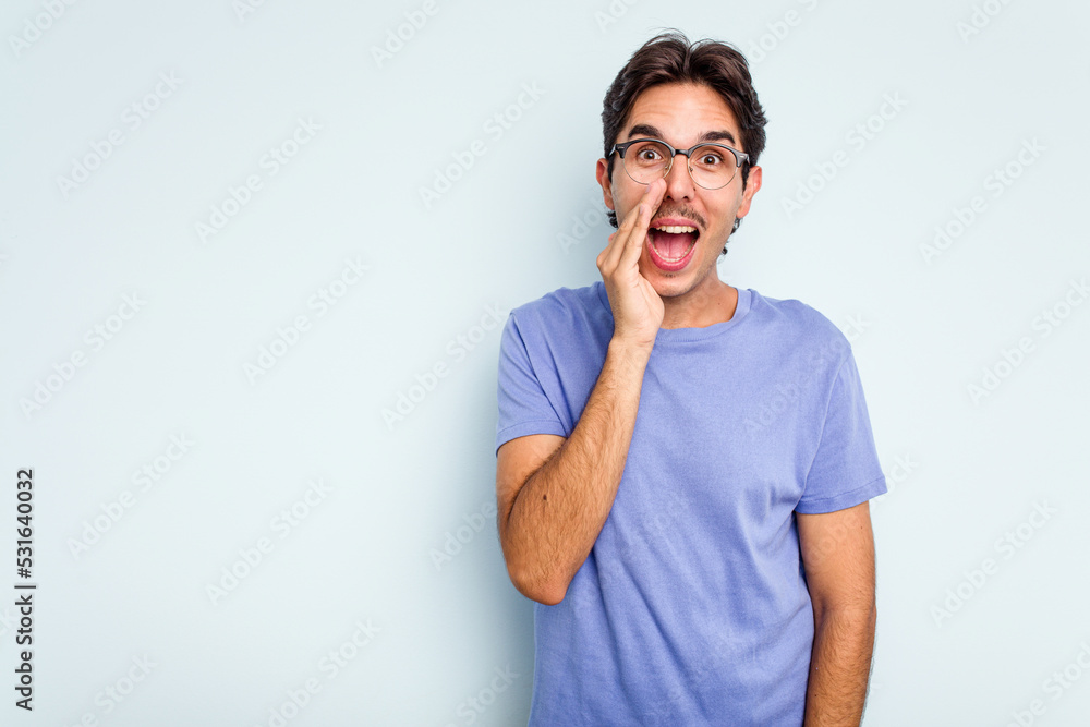 Young hispanic man isolated on blue background shouts loud, keeps eyes opened and hands tense. Young hispanic man isolated on blue background shouts loud, keeps eyes opened and hands tense.
