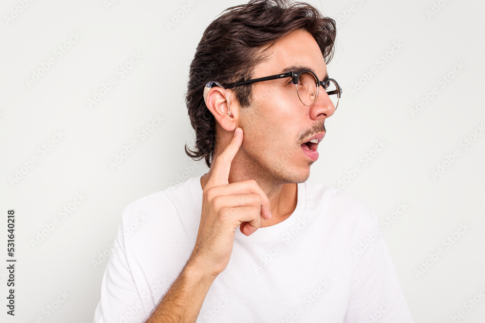 Young hispanic man wearing hearing aid isolated on white background Young hispanic man wearing hearing aid isolated on white background