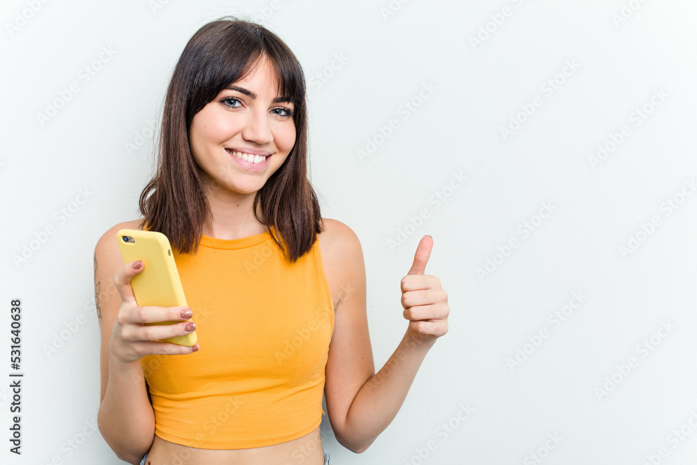 Young caucasian woman using mobile phone isolated on white background smiling and raising thumb up Young caucasian woman using mobile phone isolated on white background smiling and raising thumb up