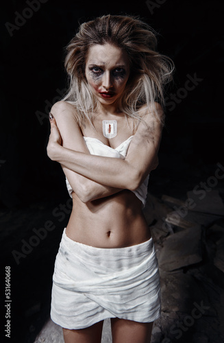 Strange crazy girl in bandages. Morbid sad young woman (freak) with messy make-up. Portrait of madman (mental sick) photo