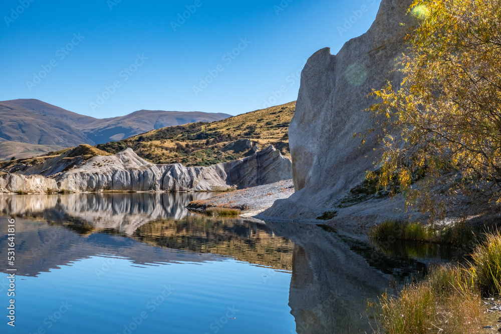 White quartz gravel cliffs reflected in the waters of the man-made Blue Lake in the Central Otago historic gold mining area of the South Island of New Zealand