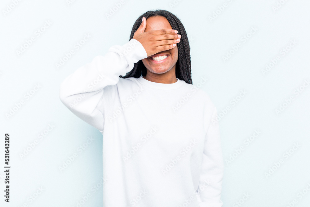 Fototapeta premium Young African American woman with braids hair isolated on blue background covers eyes with hands, smiles broadly waiting for a surprise.