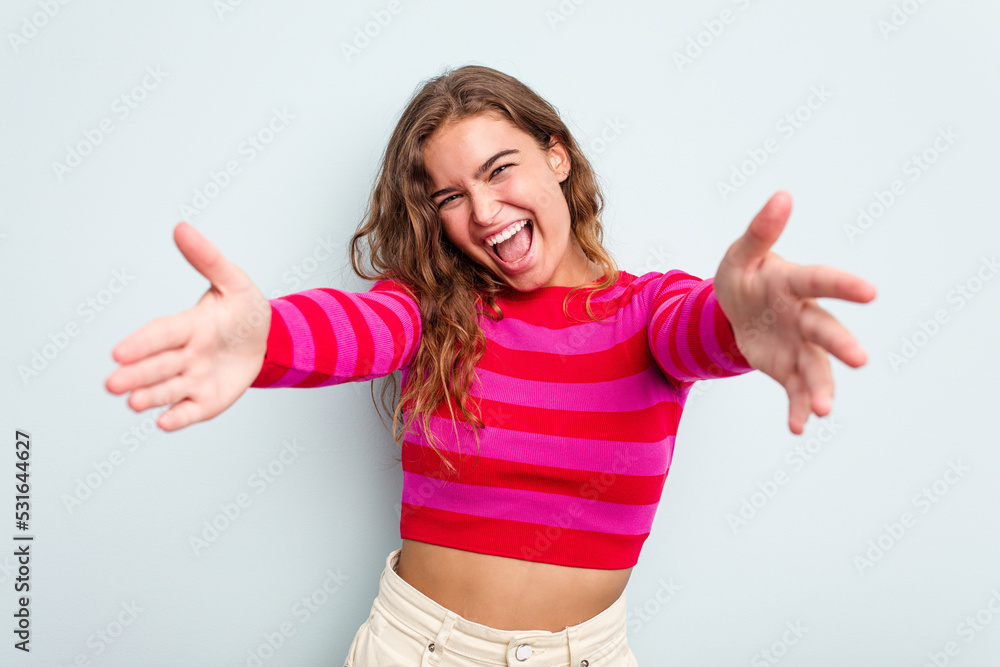 Young caucasian woman isolated on blue background feels confident giving a hug to the camera. Young caucasian woman isolated on blue background feels confident giving a hug to the camera.