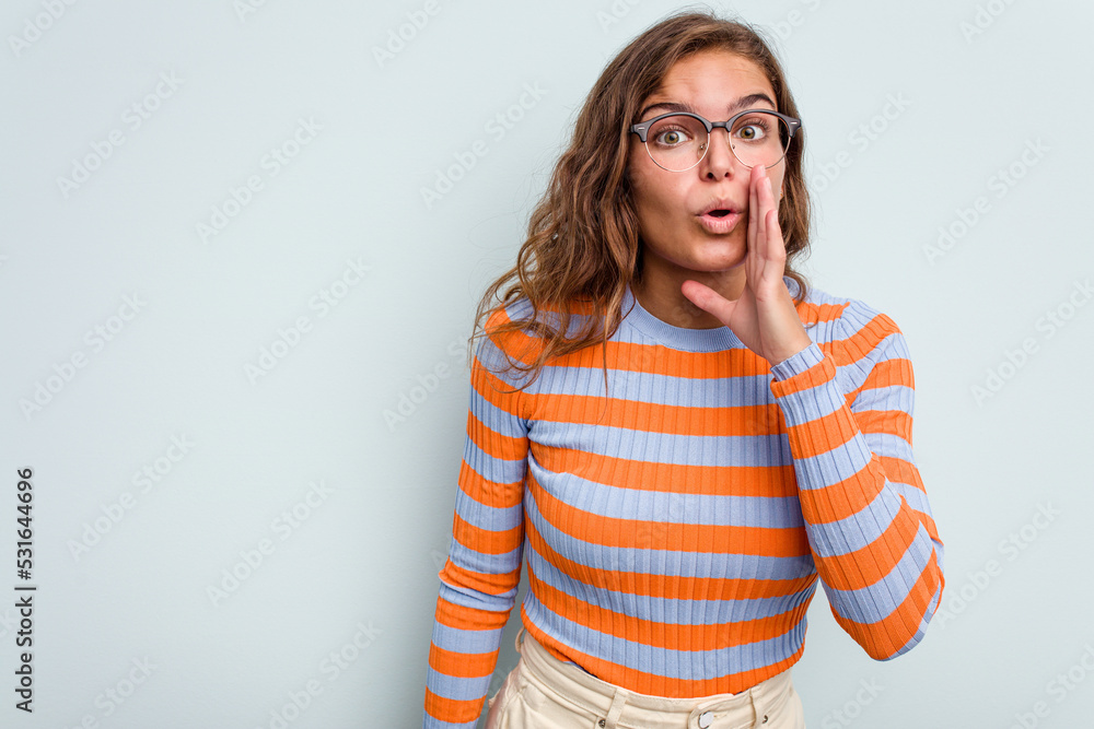 Young caucasian woman isolated on blue background is saying a secret hot braking news and looking aside Young caucasian woman isolated on blue background is saying a secret hot braking news and looking aside