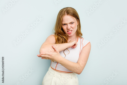 Young caucasian woman isolated on blue background massaging elbow, suffering after a bad movement.