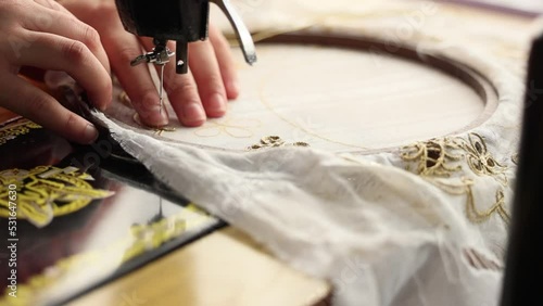 Tailor sewing on a round needlepoint canvas with golden lining photo