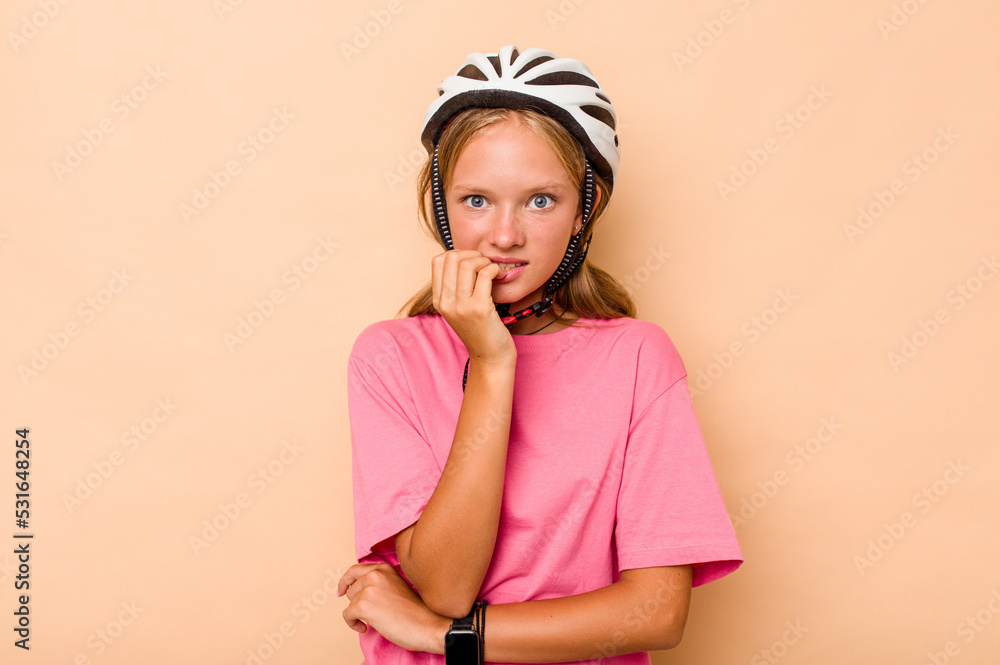 Little caucasian girl wearing a bike helmet isolated on beige background biting fingernails, nervous and very anxious. Little caucasian girl wearing a bike helmet isolated on beige background biting fingernails, nervous and very anxious.