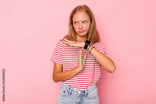 Caucasian teen girl isolated on pink background showing a timeout gesture. photo