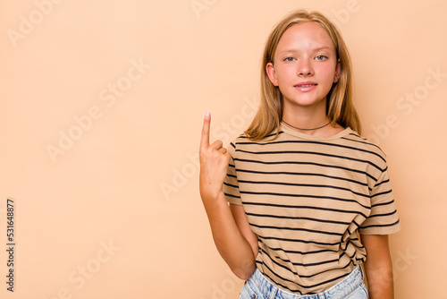 Caucasian teen girl isolated on beige background showing number one with finger.