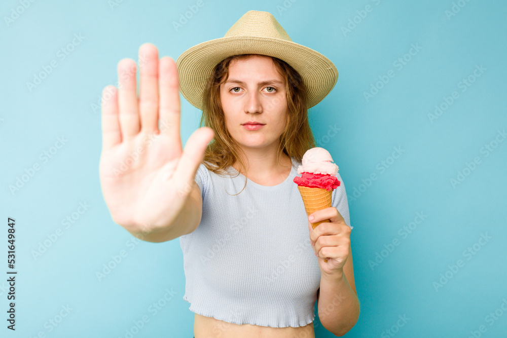 Young caucasian woman holding an ice cream isolated a blue background standing with outstretched hand showing stop sign, preventing you. Young caucasian woman holding an ice cream isolated a blue background standing with outstretched hand showing stop sign, preventing you.