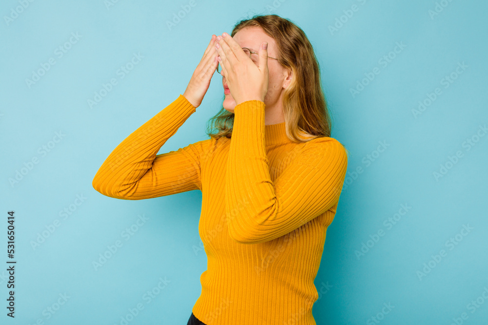 Young caucasian woman isolated on blue background afraid covering eyes with hands. Young caucasian woman isolated on blue background afraid covering eyes with hands.