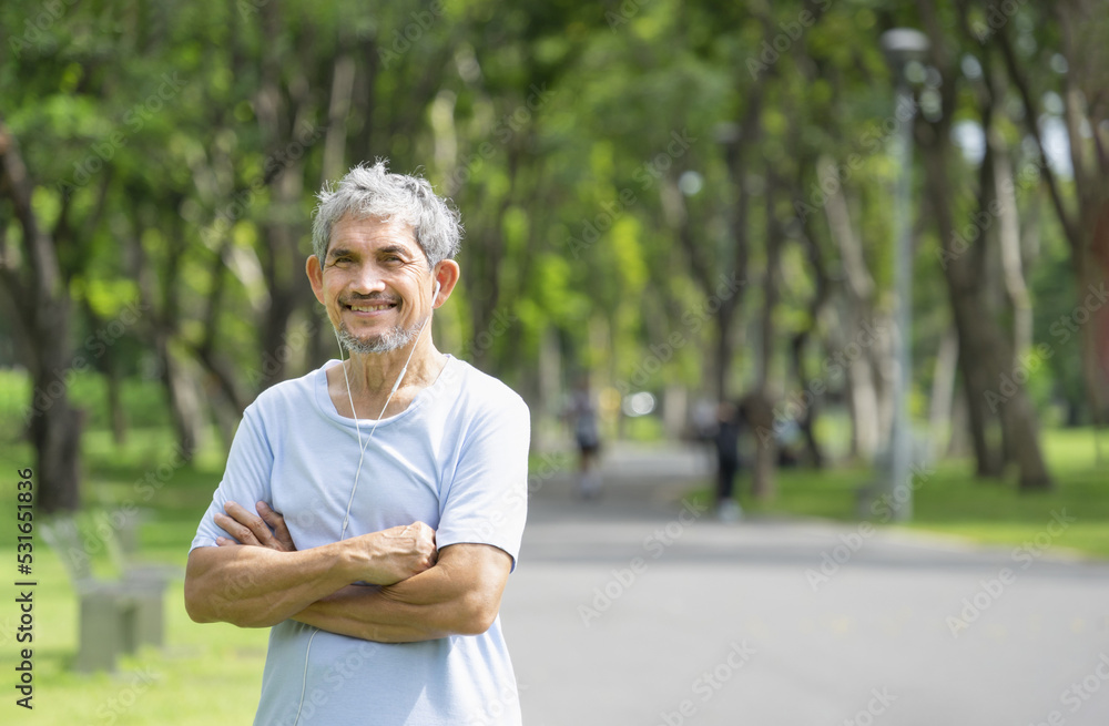 portrait senior man with grey hair wearing headphones to listen music, an old man relaxing in the park after workout portrait senior man with grey hair wearing headphones to listen music, an old man relaxing in the park after workout