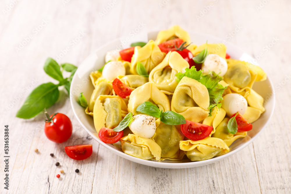 bowl of tortellini pasta with tomato,  mozzarella and basil- italian cuisine