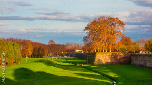 Autumn and foliage in Lucca. Anciet city walls park with autumnal leaves at sunset