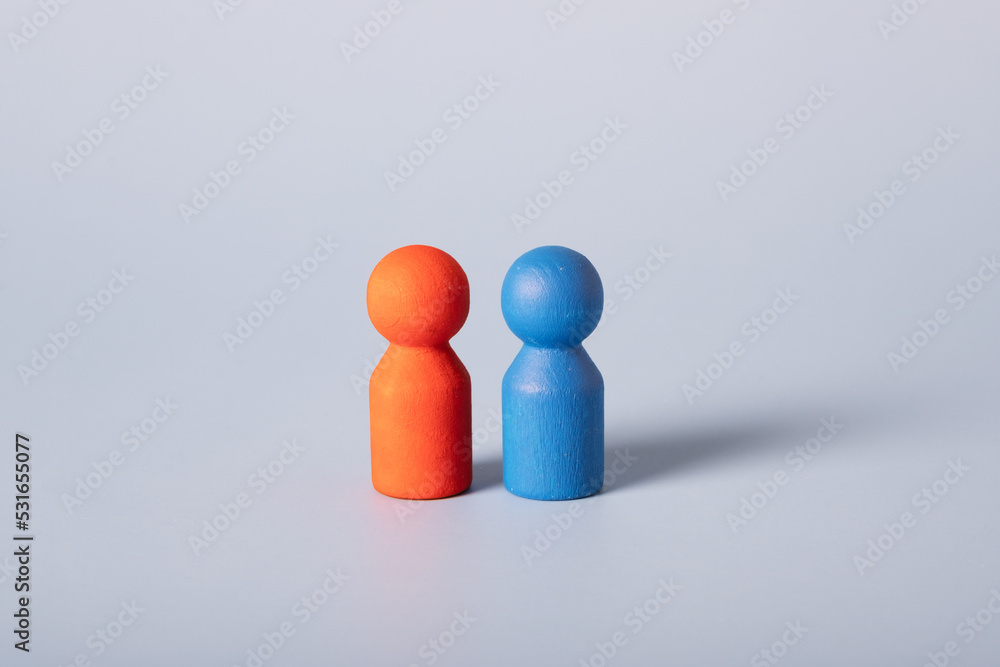 A red and blue figure stand together on a blue background. Two different sexes are male and female. A red and blue figure stand together on a blue background. Two different sexes are male and female.