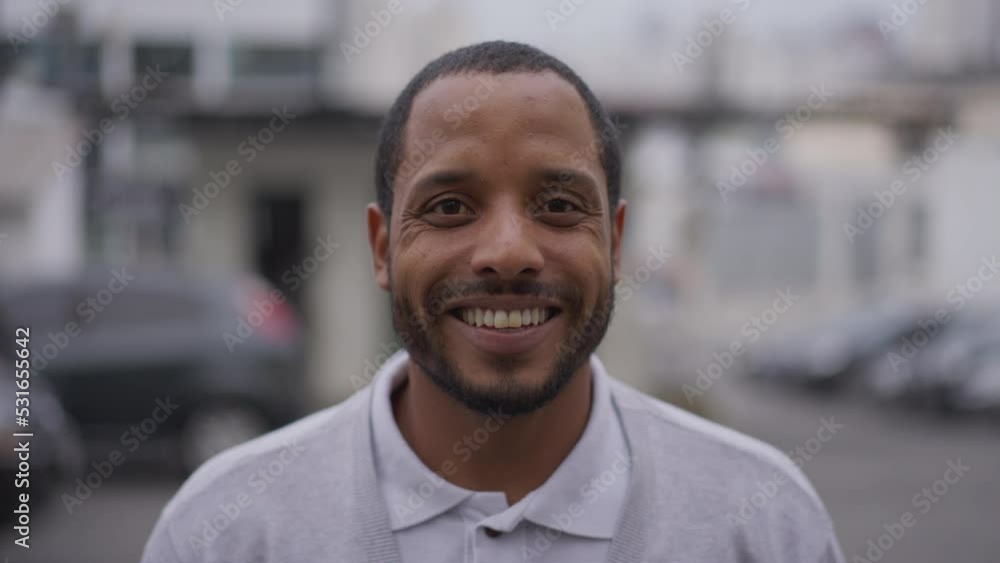 Happy African American young man looking at camera smiling. A Brazilian South American guy standing outdoors in urban street Happy African American young man looking at camera smiling. A Brazilian South American guy standing outdoors in urban street