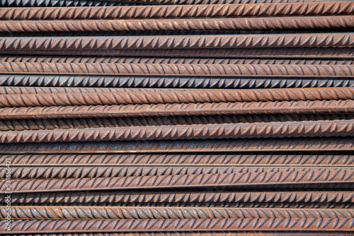 Pile of reinforcing steel bars, known also as rebars, used as construction material in reinforcing concrete or masonry work, close-up of the rusty rods with spiral ridges forming symmetrical patterns