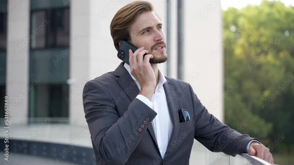 Portrait handsome man having phone talk outdoor. Business man talking on smartphone at street Portrait handsome man having phone talk outdoor. Business man talking on smartphone at street