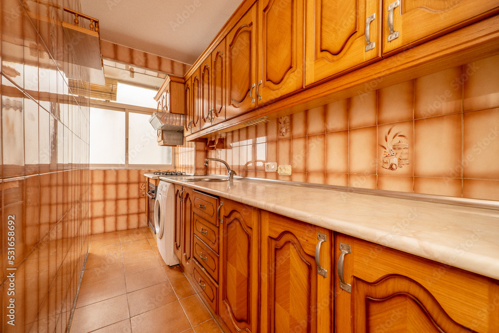 Long kitchen with cream marblelook wood countertops and orangebrown