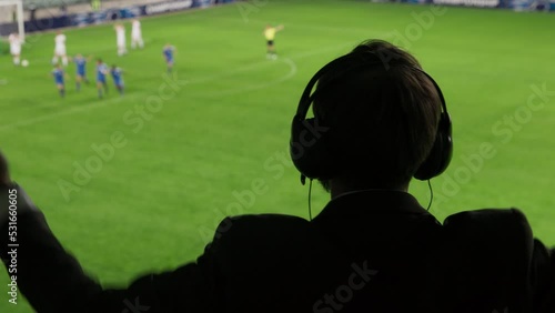 Back View Sports Commentator Analysing Soccer Match, Live Game. Silhouette of Announcer with Football Stadium and Field Before Him Commenting on the Seasons Best Moments, Talking about Top Players photo