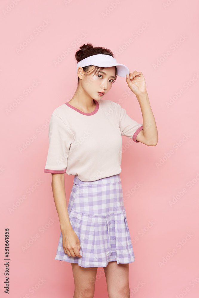 スポーティなファッションをした若い女性のピンク背景のポートレート スポーティなファッションをした若い女性のピンク背景のポートレート