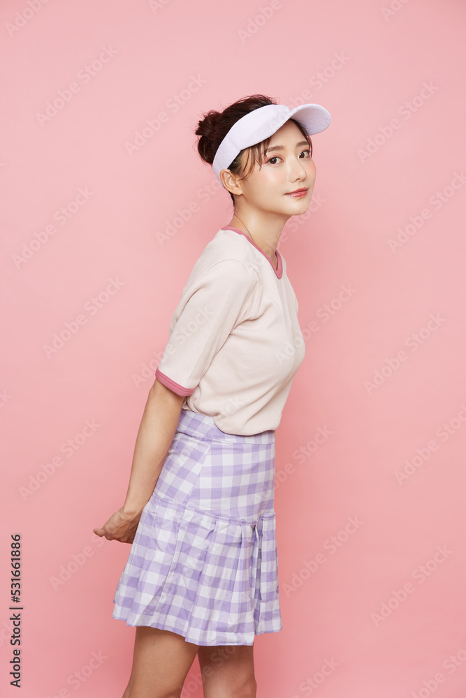 スポーティなファッションをした若い女性のピンク背景のポートレート スポーティなファッションをした若い女性のピンク背景のポートレート