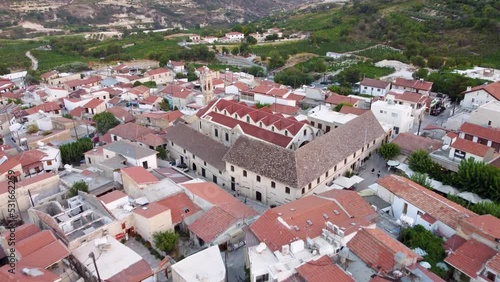 Aerial drone footage of traditional countryside village Omodos, Limassol, Cyprus. 360 reveal scene of Timios Stavros (Holy Cross) monastery, tiled roof houses and balconies, narrow streets from above. photo